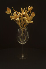 A glass vase with a bouquet of flowers made from straw on a dark background
