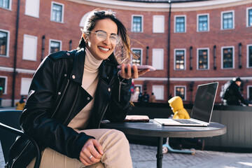 Smiling woman sitting at table and speaking on smartphone