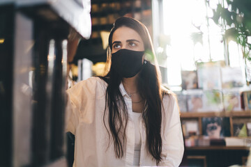 Young woman in mask in bookstore
