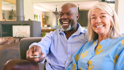 Multi-Racial Senior Couple On Sofa At Home Together Watching TV