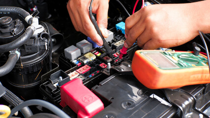 car mechanic checking the fuse connection using a multimeter and a test pen in the car fusebox