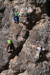 Tres escaladores practican alpinismo y suben una pared de roca.