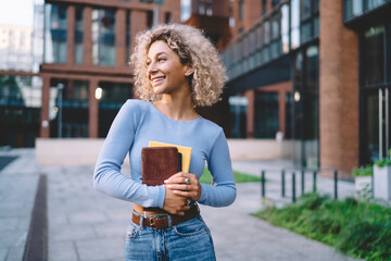 Smiling woman with books standing in campus