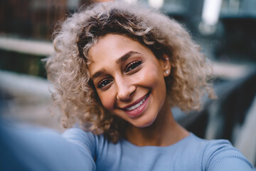 Positive woman looking at camera while taking selfie