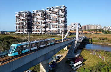 Aerial view of a metro train of Danhai Light Rail Transit traveling across a bridge with...