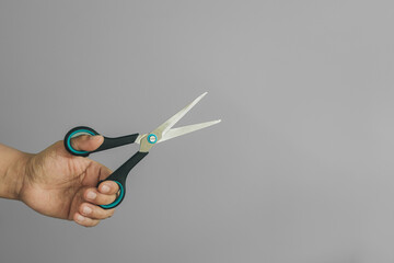 Hand of a left-handed person holding a scissors, with copy space