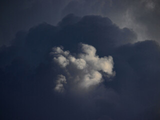 Fototapeta na wymiar The top of a dark gray shaded cloud lit by sunbeam.