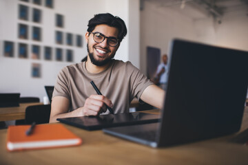 Smiling ethnic man with graphic tablet