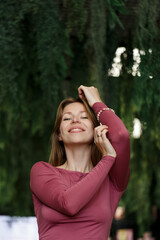 Happy young woman looking at camera. Portrait of comfortable woman relaxing on armchair. Portrait of beautiful girl smiling and relaxing on green plants background.