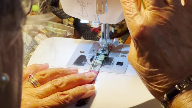 A close up view of an elderly woman using a sewing machine.  	