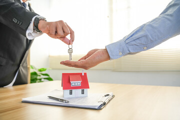 A real estate agent gives the client the house keys after signing a real estate contract with an...