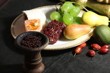 bowl with tobacco for hookah. shisha smoking. berries and fruits on a black background.