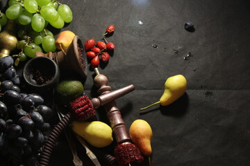 bowl with tobacco for hookah. shisha smoking. berries and fruits on a black background.