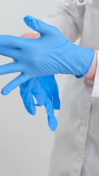Two blue surgical medical gloves, insulated on a white background with hands. Producing rubber gloves, human hand wears a latex glove. Doctor or nurse wears nitrile protective gloves