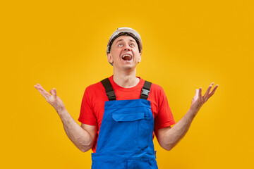 Middle-aged man wears industrial engineer clothes throws up his hands in despair and screams. Male...