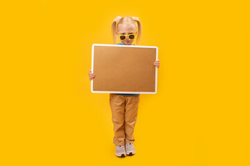Child holds blank cork board. Blonde girl in sunglasses holds board with space for your text....