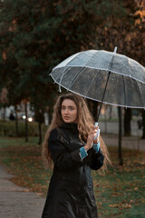 Beautiful blue-eyed girl with wavy hair looks wistfully to side. Young woman holding umbrella in hands. Vertical frame.