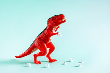 Red toy dinosaur with coffee cups on blue background. Coffee addiction concept.