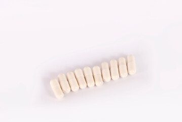 Fototapeta na wymiar White pills in capsules on a white background. Medical capsule pills, top view. Packaging for tablets, capsules or supplements. The concept of medicine and health. Vitamins for health and sports