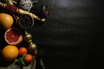 bowl with tobacco for hookah. shisha smoking. berries and fruits on a black background.