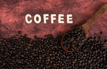 Coffee beans with wooden spoon isolated on brown colour background