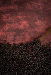 Coffee beans with wooden spoon isolated on brown colour background