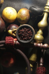 bowl with tobacco for hookah. nargile smoking. berries and fruits on a black background.