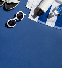 Summer vacation beach concept frame with retro sunglasses and striped towel on the blue background. Copy space	