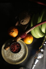 bowl with tobacco for hookah. narghile smoking. berries and fruits on a black background.