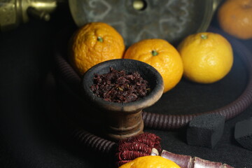 bowl with tobacco for hookah. narghile smoking. berries and fruits on a dark background.