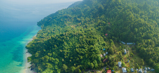 Aerial drone view of tropical island scenery with lush green forest trees at Tinggi Island or Pulau Tinggi in Mersing, Johor, Malaysia