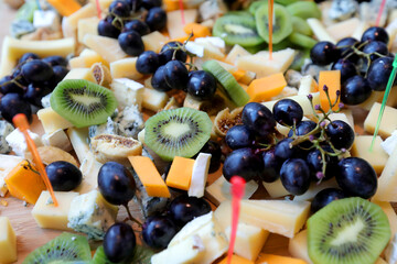 Assorted cheeses on a plate.Parmesan cheese, blue cheese and brie on a plate with grapes, kiwi and figs.  Selective focus.