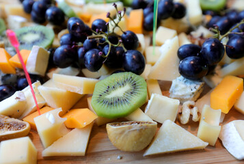 Assorted cheeses on a plate.Parmesan cheese, blue cheese and brie on a plate with grapes, kiwi and figs.  Selective focus.
