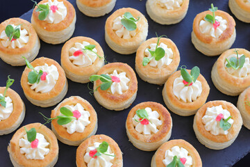 Appetizer puff pastry stuffed with soft cream cheese decorated with fresh micro plants. Selective focus.