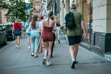 Modern fashon, woman in tight dress with perfect behind is walking on a street in Krakow, Poland. Tight red dress in public spaces, nice body and space between thighs.