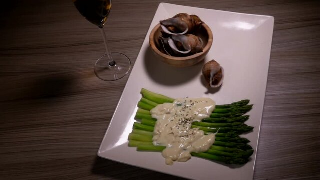 Panorama of wine and cooked sea escargo snail with side dish of boiled asparagus