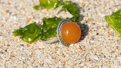 Yellow Baltic amber ring in silver on the beach.  Old handmade amber jewelry. Slavic culture.