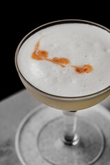 Pisco Sour a delicious cocktail served in a coupe glass on a bar table with a dark background
