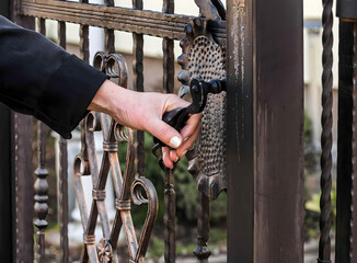Fence. Woman Hand opening Wrought metal fence gate	
