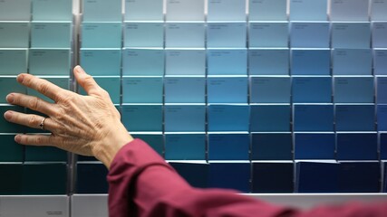 Closeup of womans hands looking at paint chips in a hardware store. Concept of home remodeling shopping experience.