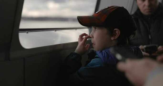 Young boy picking nose while on public transportation ferry