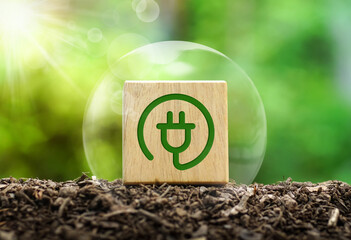 Green power plug icon on wooden cube on natural background, Green energy, clean energy. Energy saving concept.