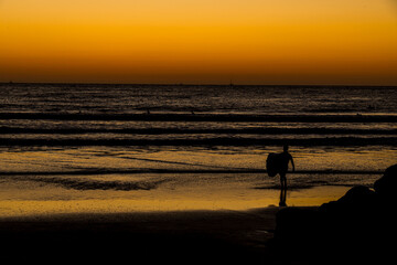 Surfer Heading into the Surf at Sunset