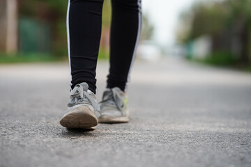 Fototapeta na wymiar Women's feet in sneakers walk on asphalt