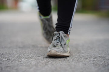 Women's feet in sneakers walk on asphalt
