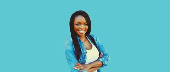 Portrait of happy smiling young african woman with crossed arms isolated on blue background