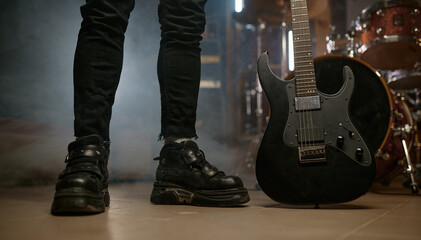 Cropped view on rocker feet legs on stage with electric guitar