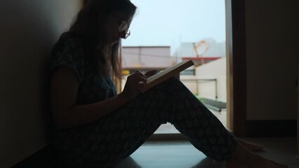 Silhouette shot of teenager girl student reading book while sitting at home during exams. Student girl reads a book before the exam. Education concept