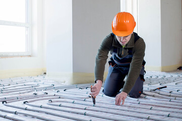 Worker is installing underfloor heating system. Warm floor heating system