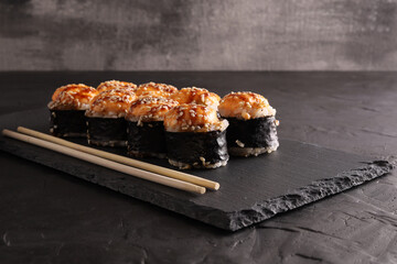 Sushi and rolls set on a black plate and black background